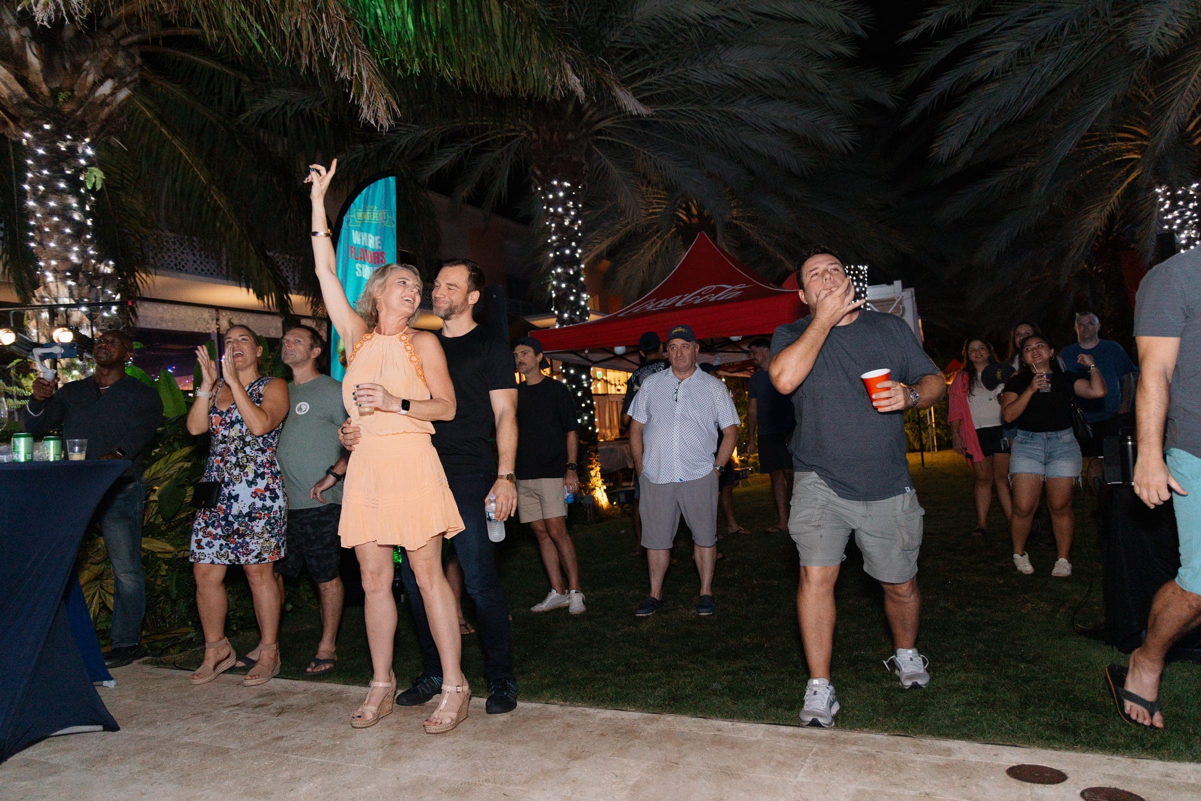 Guests dancing on the lawn at night in front of red event tents