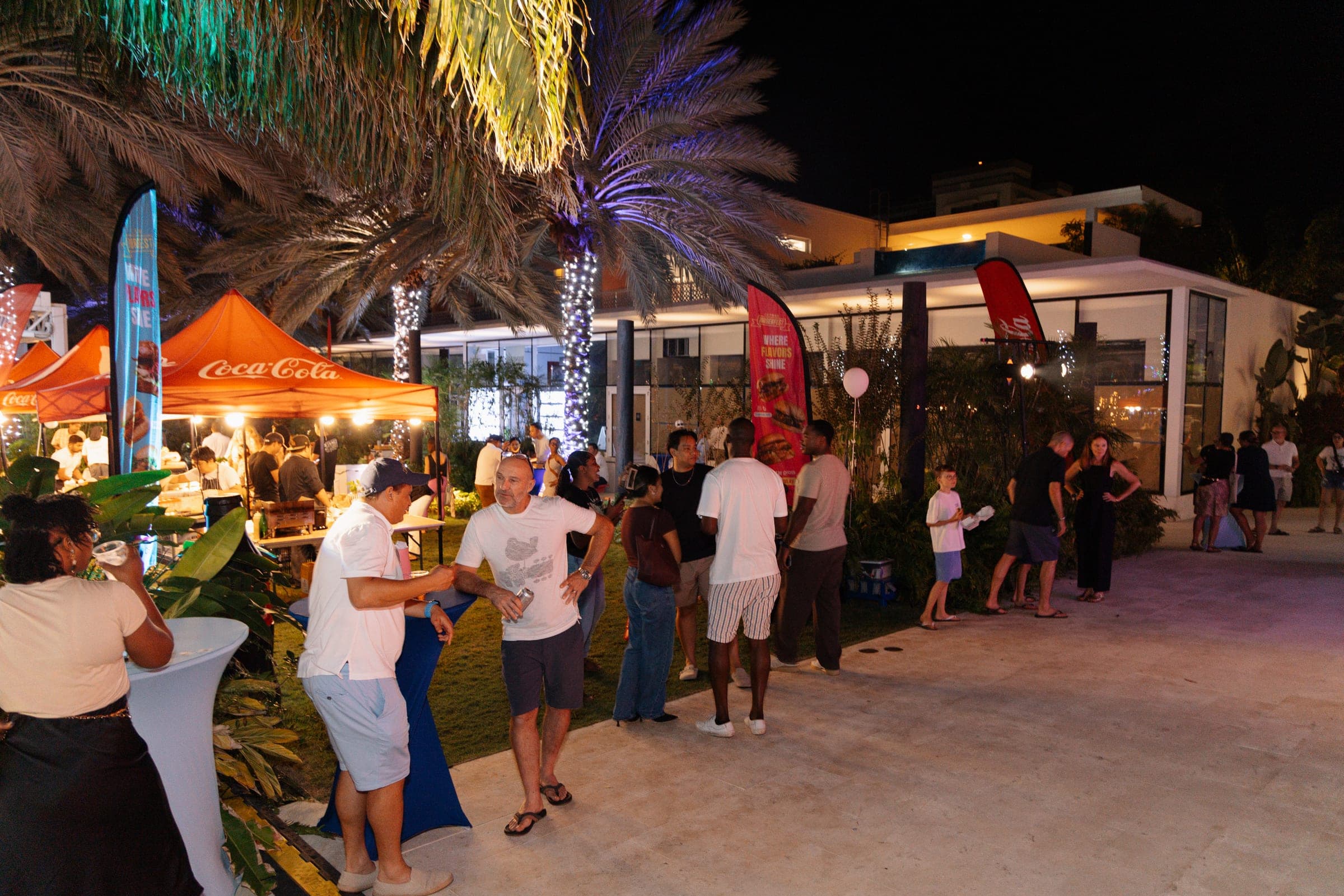 Guests mingling between lit food stalls and flag banners at The Grove at night
