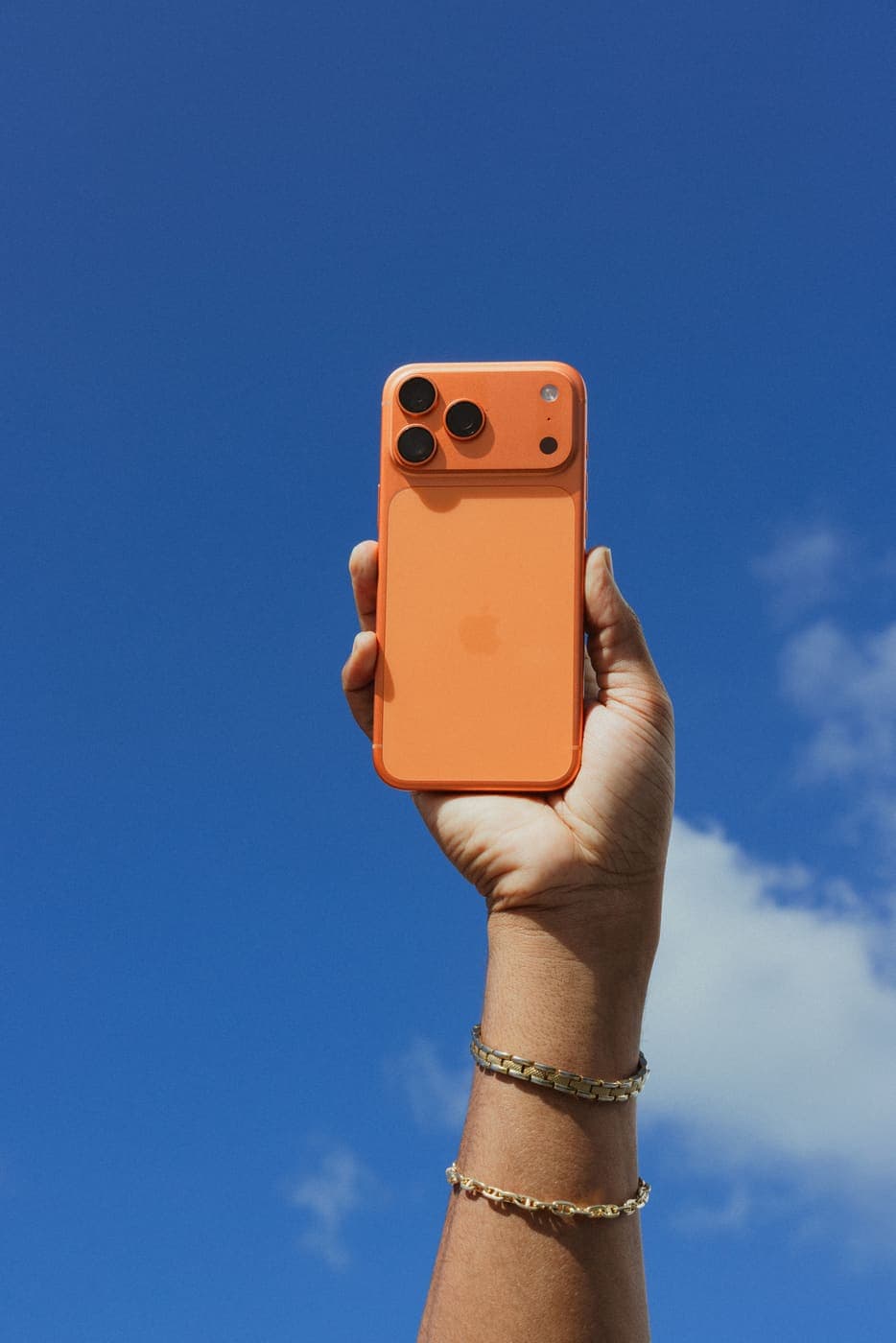 An orange iPhone 17 giveaway prize held up against a blue sky