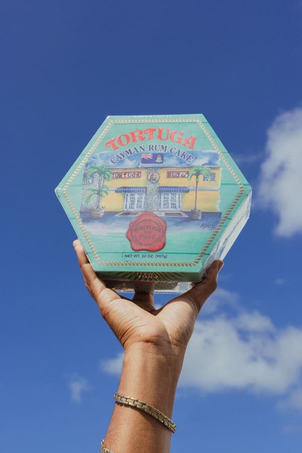 A Tortuga rum cake prize held up against a blue sky