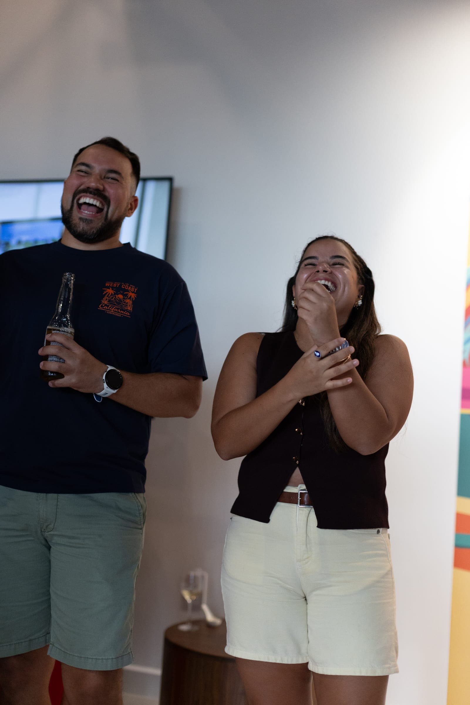 A man and a woman laughing together beside a colourful mural at the Flow store opening