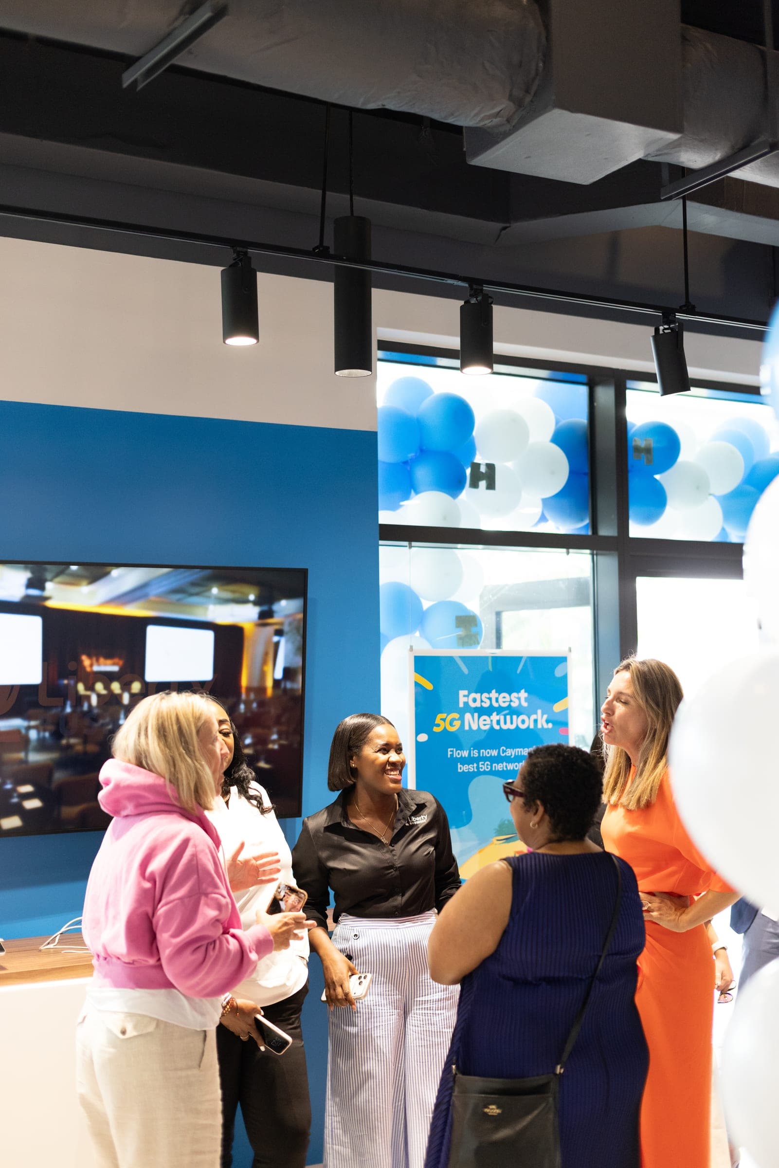 Guests talking in the busy new Flow store, with balloons and a Fastest Network sign