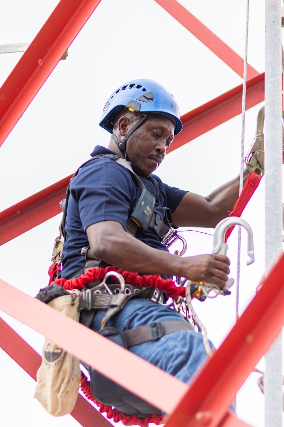A Flow engineer in a harness climbing a red and white tower