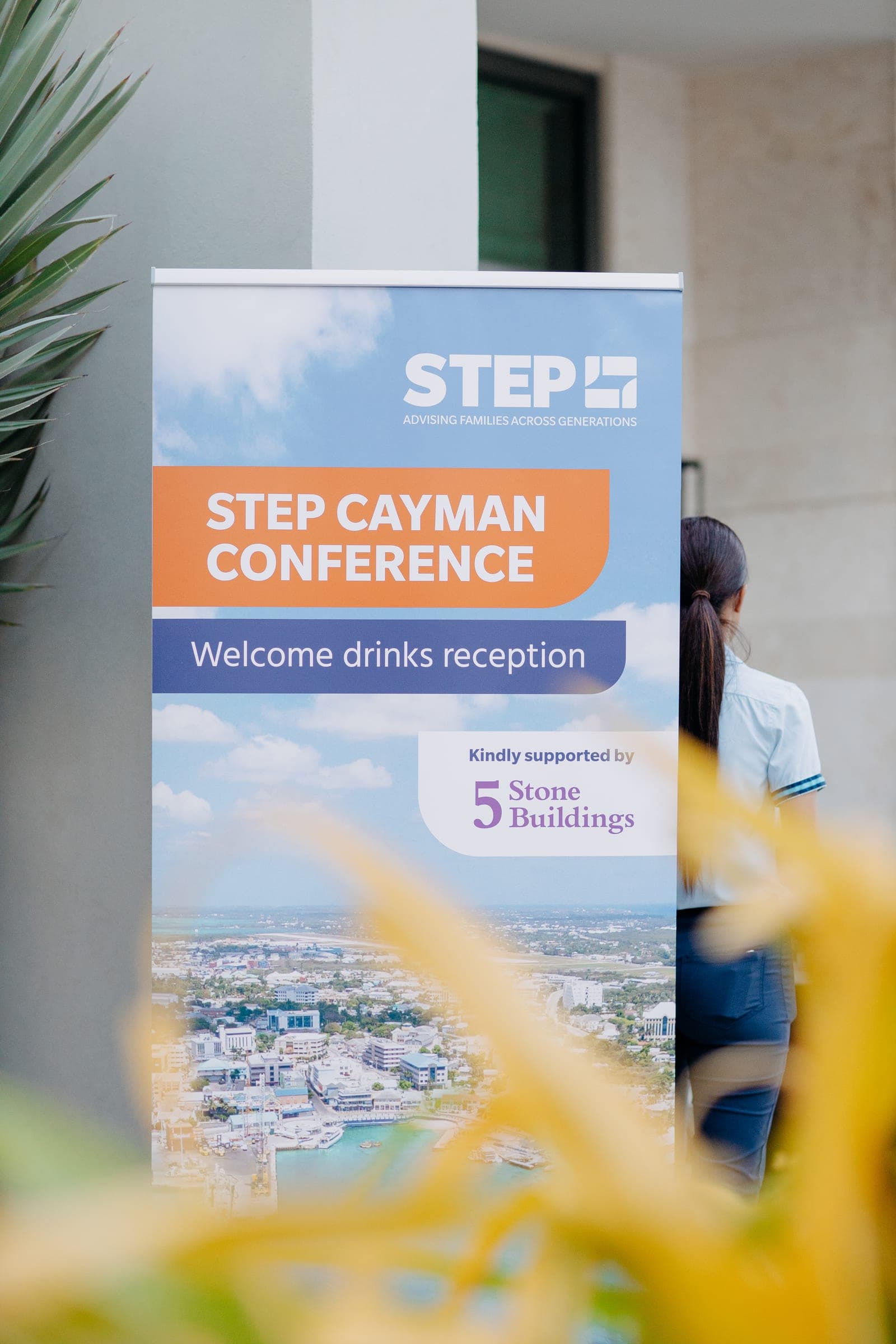 STEP Cayman Conference roll-up banner for the welcome drinks reception, framed by tropical leaves